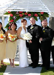 wedding party under arch with roses.